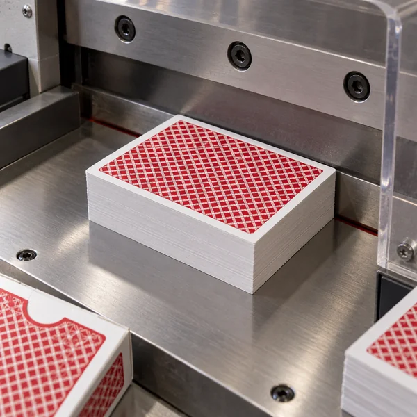 AI illustration of a card stack beneath a guarded cutting machine